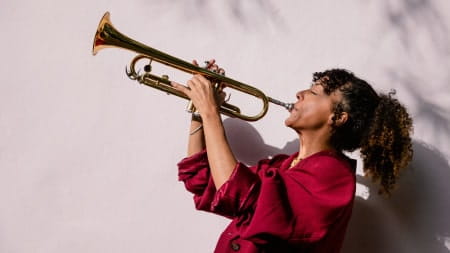 Woman wearing red jumper playing a brass trumpet