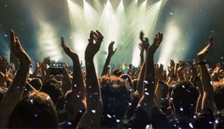 People at a concert hold up their hands during a live performance of a band on stage 