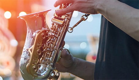 Male musician in dark t-shirt playing saxophone at outdoor summer gig
