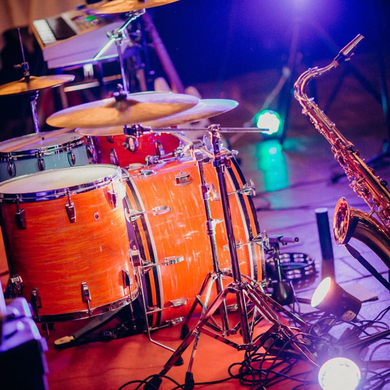 A set of drums and a saxophone sit on stage unattended