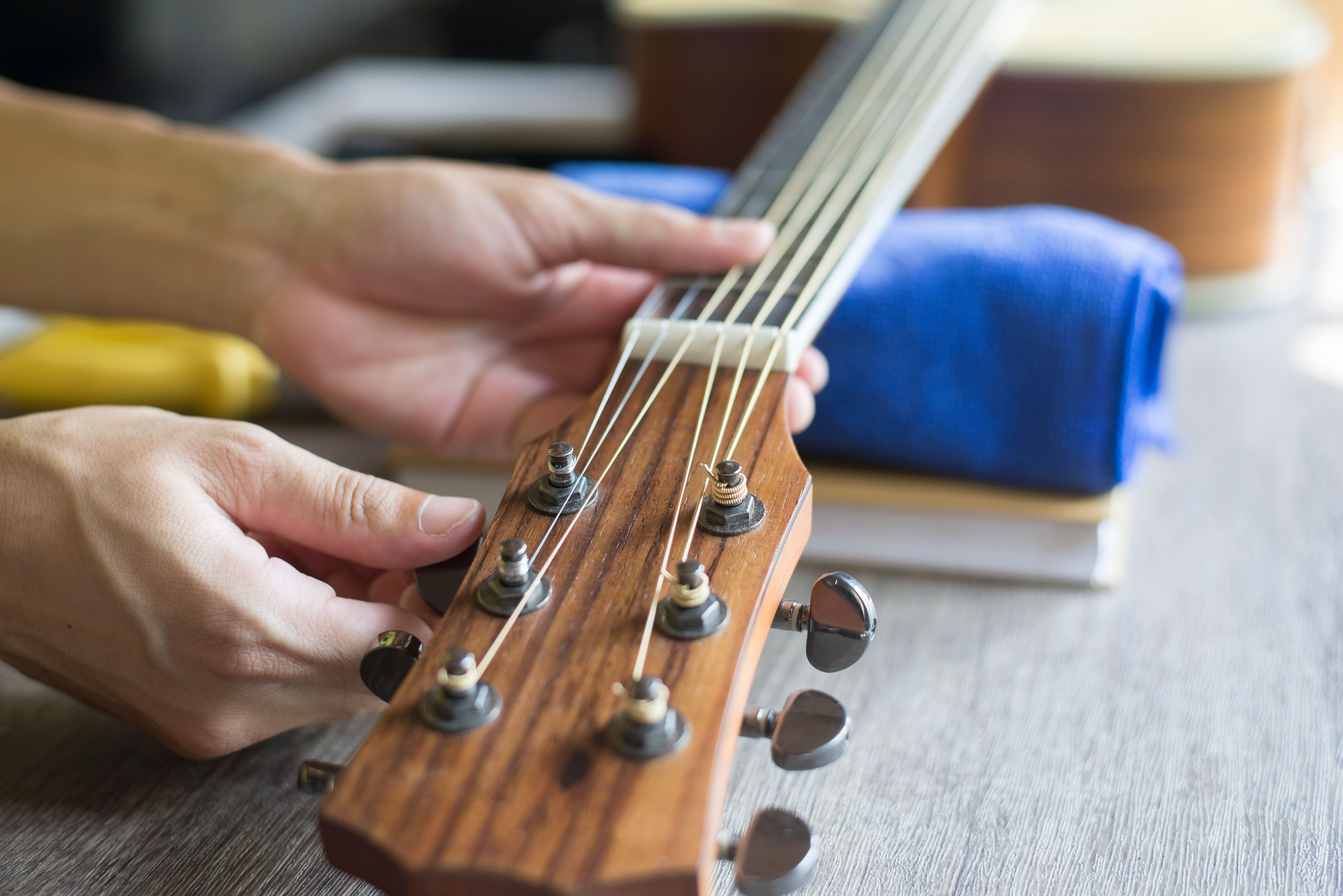 Man turning tuning peg on acoustic guitar